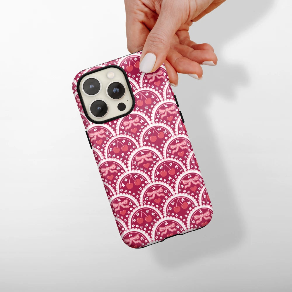 A hand with manicured nails holds a smartphone with a pastel holographic phone case. The phone case reflects light, creating a swirl of colors in pink, purple, and blue tones. The background is plain white.