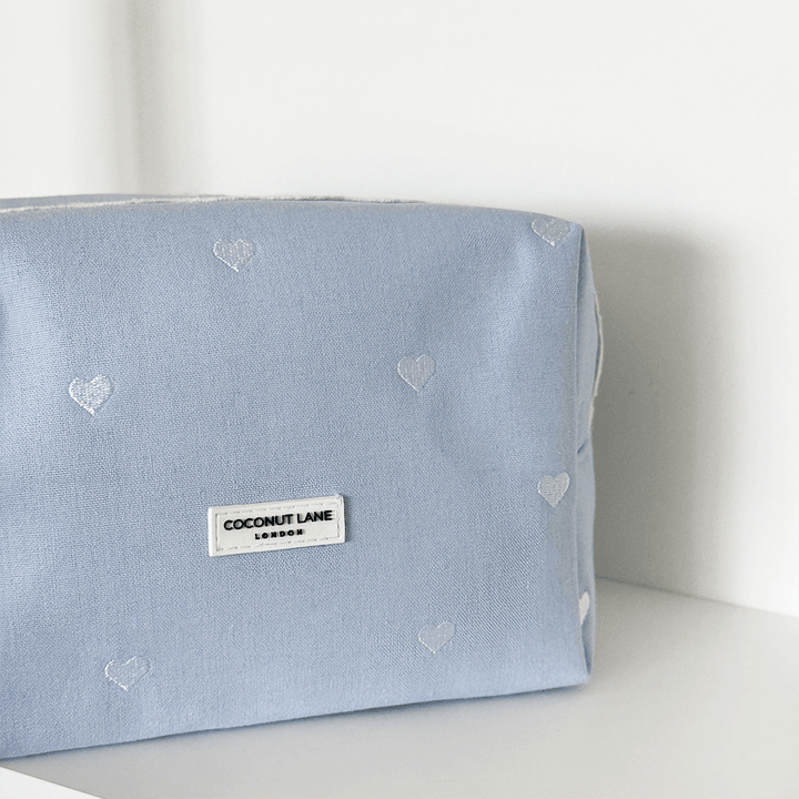 Blue fabric Makeup Bag with embroidered heart design and white lace trim.