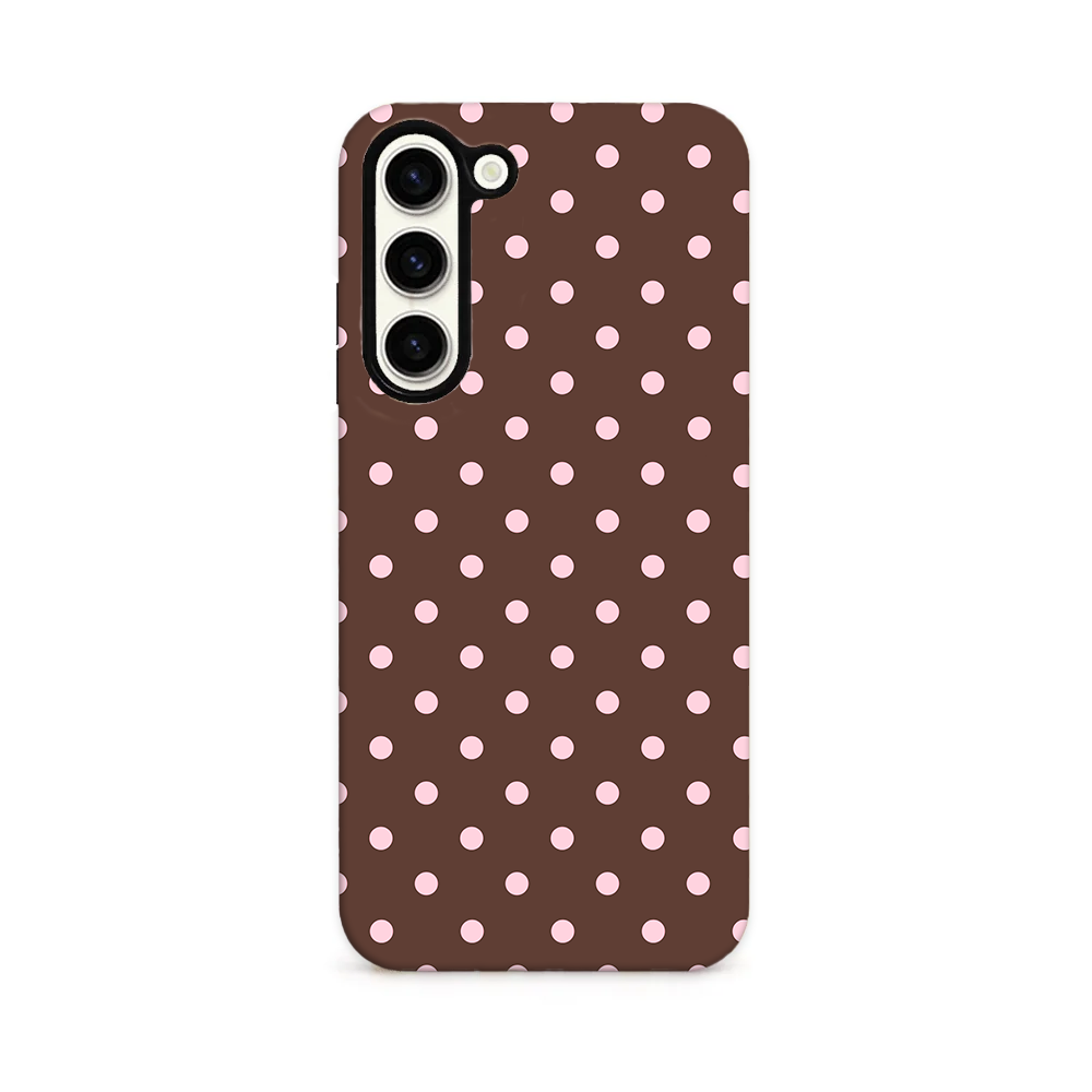 Phone case with pink polka dots on a brown background.