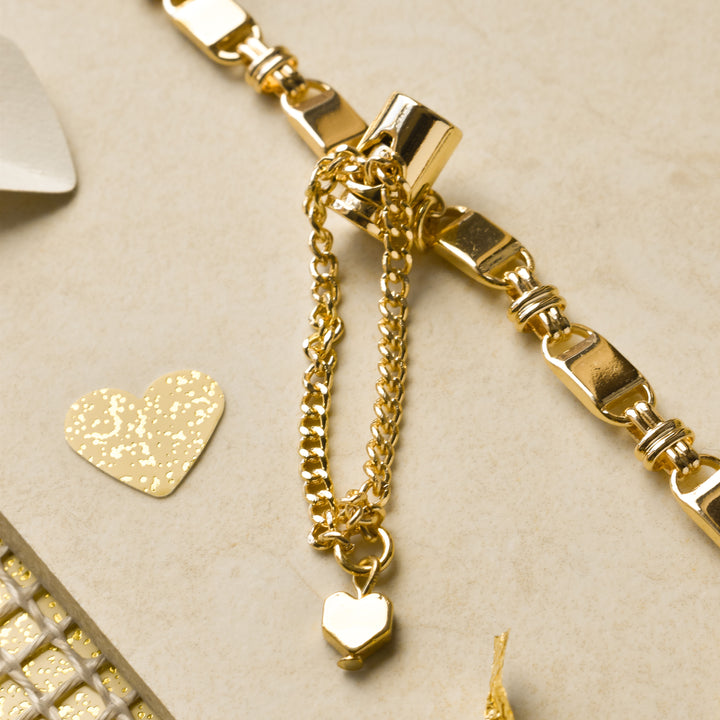The Simple Gold Bracelet Apple Watch Strap by Coconut Lane is elegantly displayed on a beige surface. Beside the strap, small decorative gold hearts and a mesh-patterned background enhance the luxurious and delicate appearance of this jewelry piece.