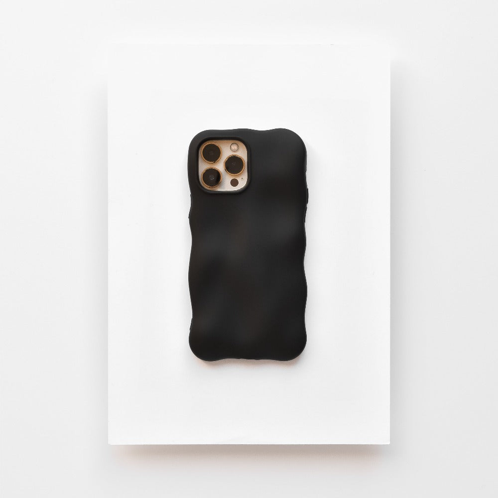A Coconut Lane smartphone enclosed in a 3D Boujee Phone Case - Matte Black is placed on a white surface. The phone's rear camera, featuring three lenses and a flash, is visible through a cutout in the extra protective case. The overall layout exudes a minimalist and modern aesthetic.