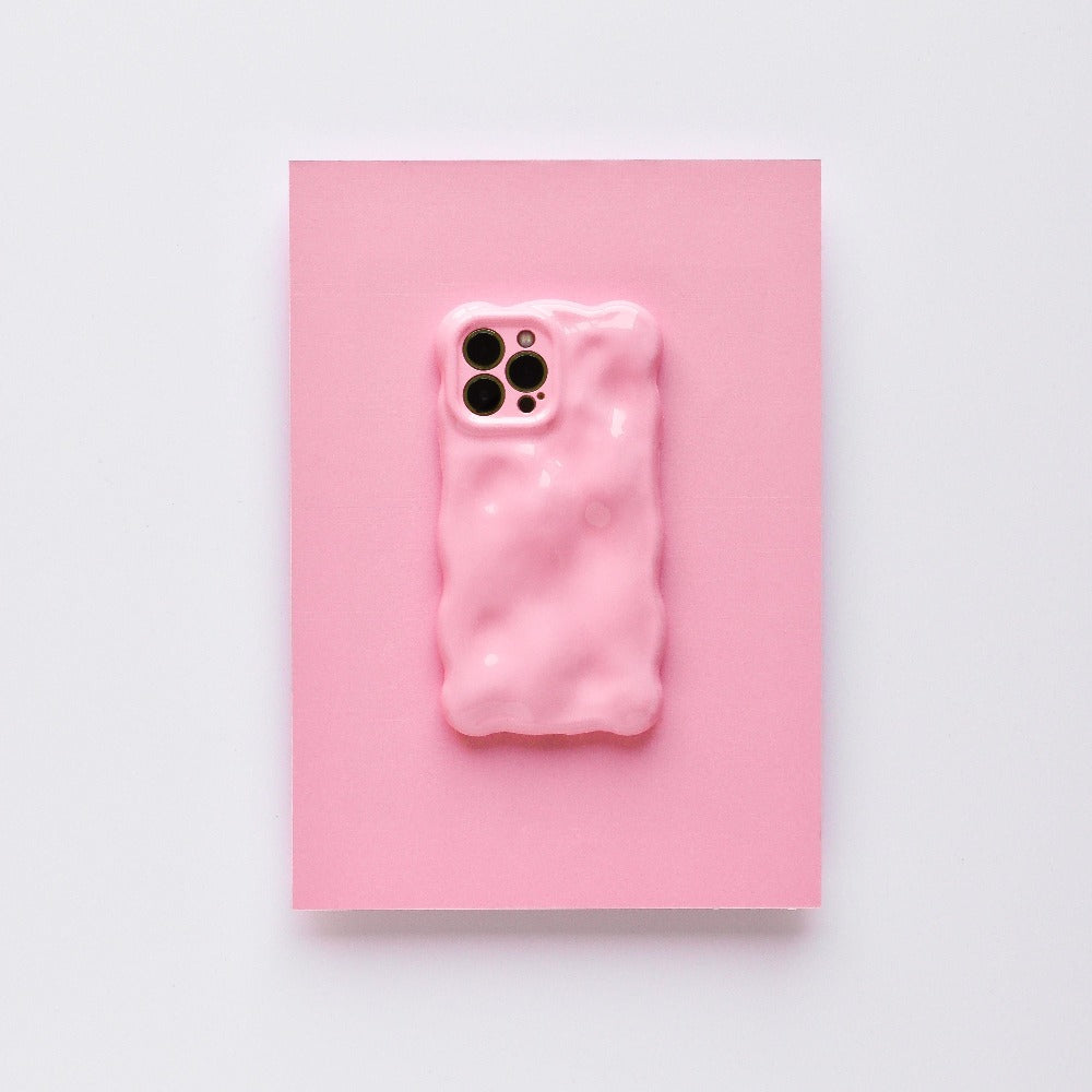 A 3D Gummy Phone Case - Pink by Coconut Lane is displayed on a pink background. This chic phone case, with its wavy, bubble-like design and glossy finish, features cutouts for the camera lenses. It offers extra protective coverage while maintaining a minimalist aesthetic with a cohesive pink theme.