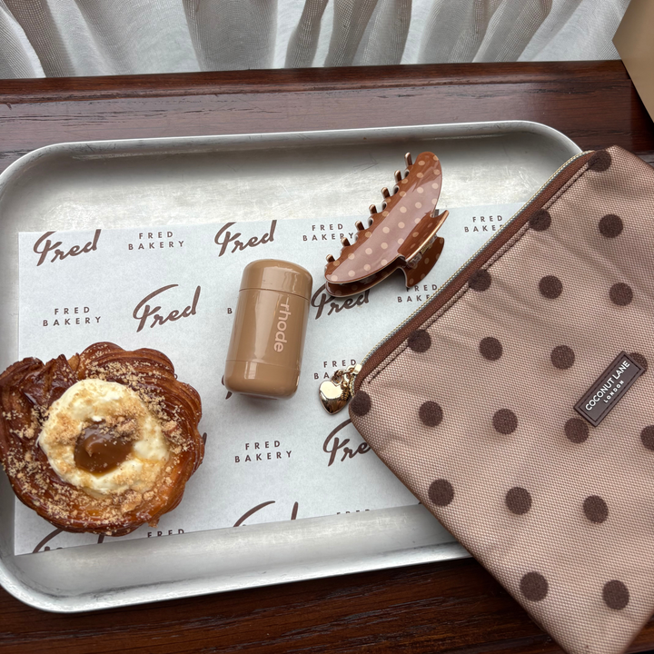 flat lay photo in a cafe, showing the Dot Society Chocolate Brown claw clip, alongside the matching Everything Pouch. 