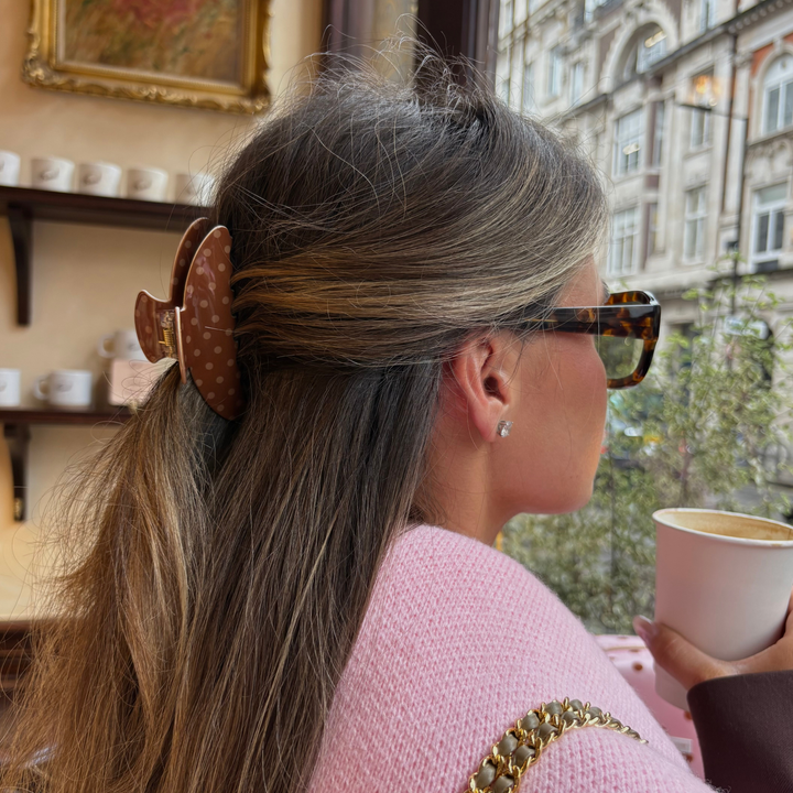 Woman with long wavy brunette hair. In her hair is the Dot Society Chocolate Brown polka dot claw clip.