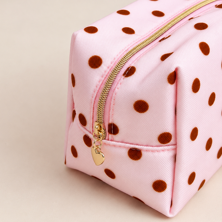 Close-up of pink mesh makeup bag with brown polka dots and a gold top zip with a heart-shaped zip pull.