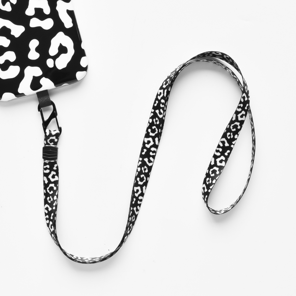 The Universal Phone Lanyard Patch Bundle by Coconut Lane is displayed on a white surface, featuring a chic black and white abstract leopard print design. This stylish phone accessory includes a clip at one end and connects to a rectangular badge holder with the same matching pattern, seamlessly blending fashion with phone security.
