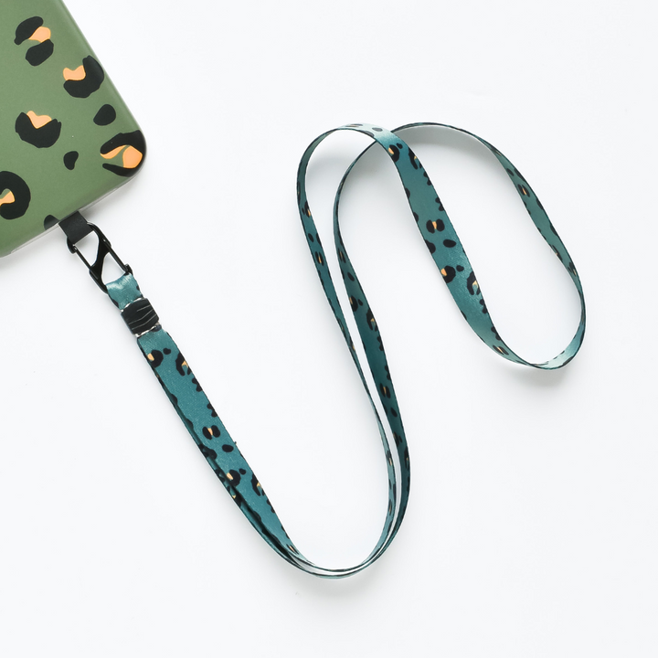 Introducing the Universal Phone Lanyard Patch Bundle by Coconut Lane: A smartphone case in green, adorned with a striking black and orange leopard print design. Complementing this is a detachable, teal blue lanyard featuring a matching leopard print pattern, elegantly draped in a loose curve against a white background. This bundle is the perfect phone accessory for added style and security.