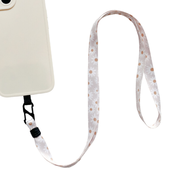 A stylish phone accessory from Coconut Lane, the Universal Phone Lanyard Patch Bundle features a cream-colored smartphone case paired with a floral lanyard adorned with daisy patterns. The patch loops and extends from the bottom of the case, enhancing phone security. The product image is set against a white background.