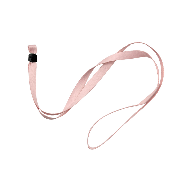 A soft pink ribbon with a black binding at one end, resembling the Coconut Lane Universal Phone Lanyard Patch Bundle, is looped and laid out on a white background.