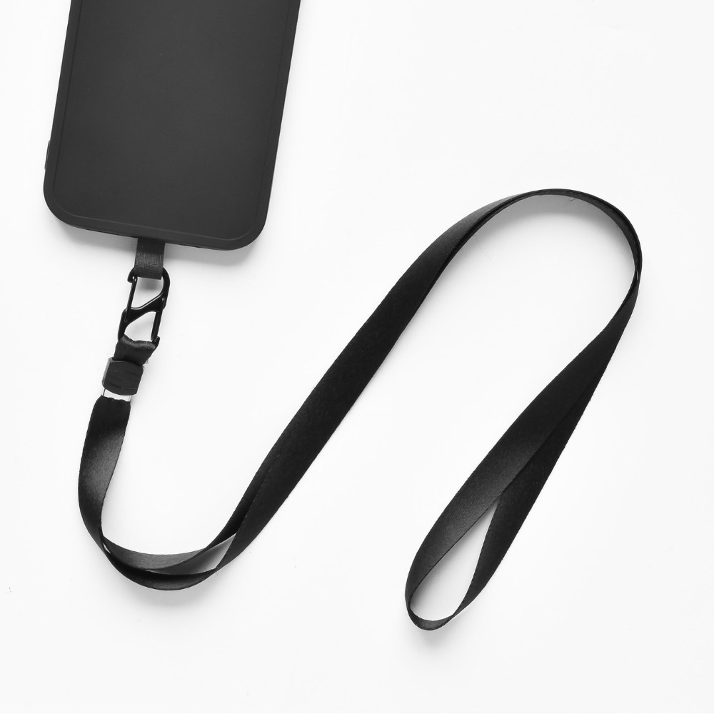A black smartphone case is shown attached to a long, black lanyard with a clasp, providing added phone security. The case has a simple design with no visible branding or pattern. This Universal Phone Lanyard Patch Bundle by Coconut Lane is laid out in a loose, curving manner on a white background.