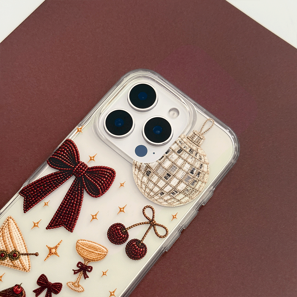 A clear phone case decorated with party-themed graphics including a large burgundy bow, a martini glass, cherries, a strawberry, a disco ball, and small gold stars.