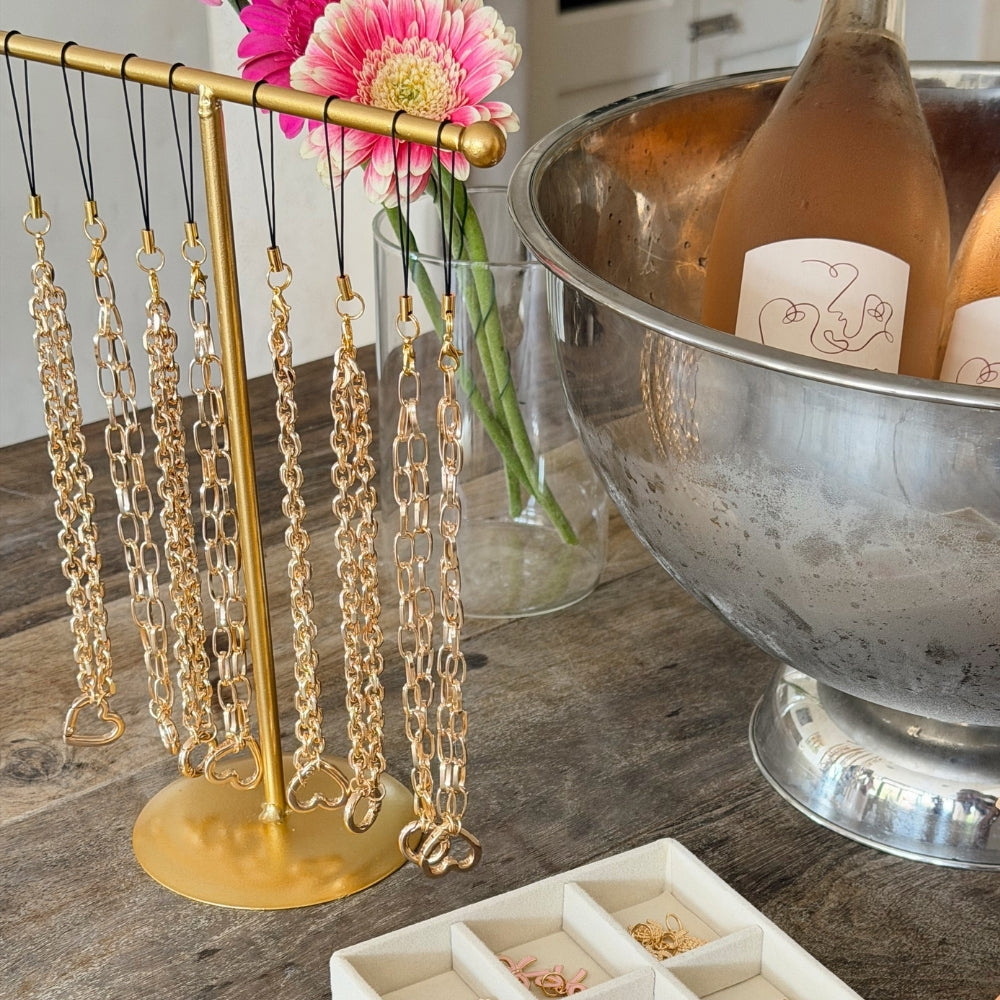 Gold stand showing the different phone straps from the charm studio.