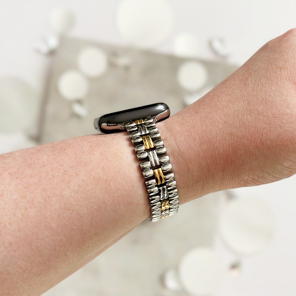 Slim stainless steel Apple Watch strap in vintage gold and silver, shown worn on a wrist.