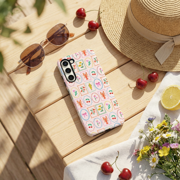 Samsung Tough Phone Case - Dolce Vita by Coconut Lane on a picnic table with sunglasses, hat, cherries, flowers and lemon slice.