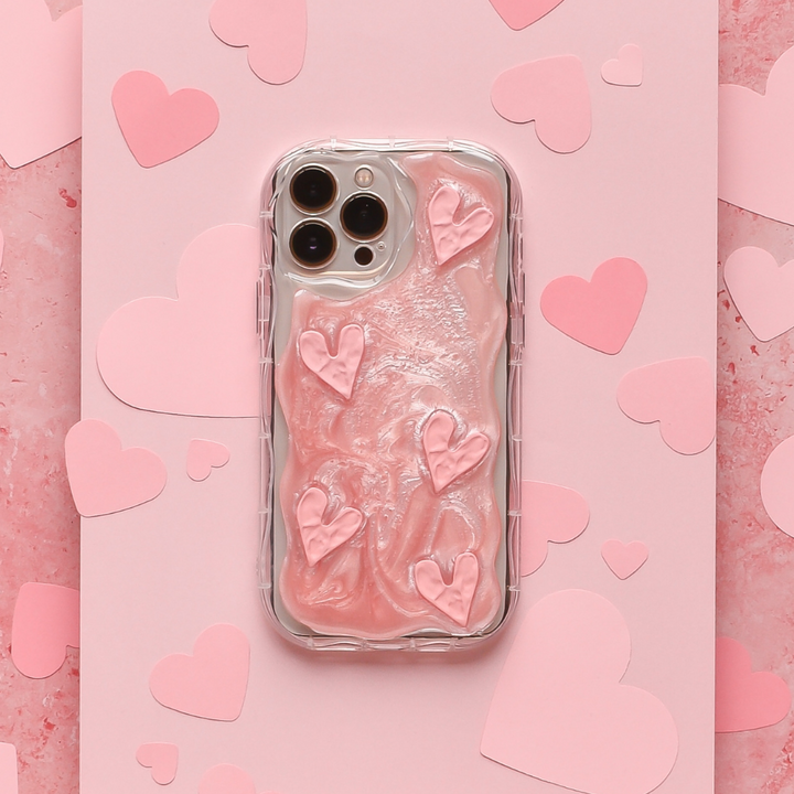 A Coconut Lane Shimmer Pink Hearts Phone Case, snugly fitting a smartphone, lies on a pink, textured background. Additional paper hearts in various shades of pink are scattered around the phone, creating a romantic, heart-themed scene.
