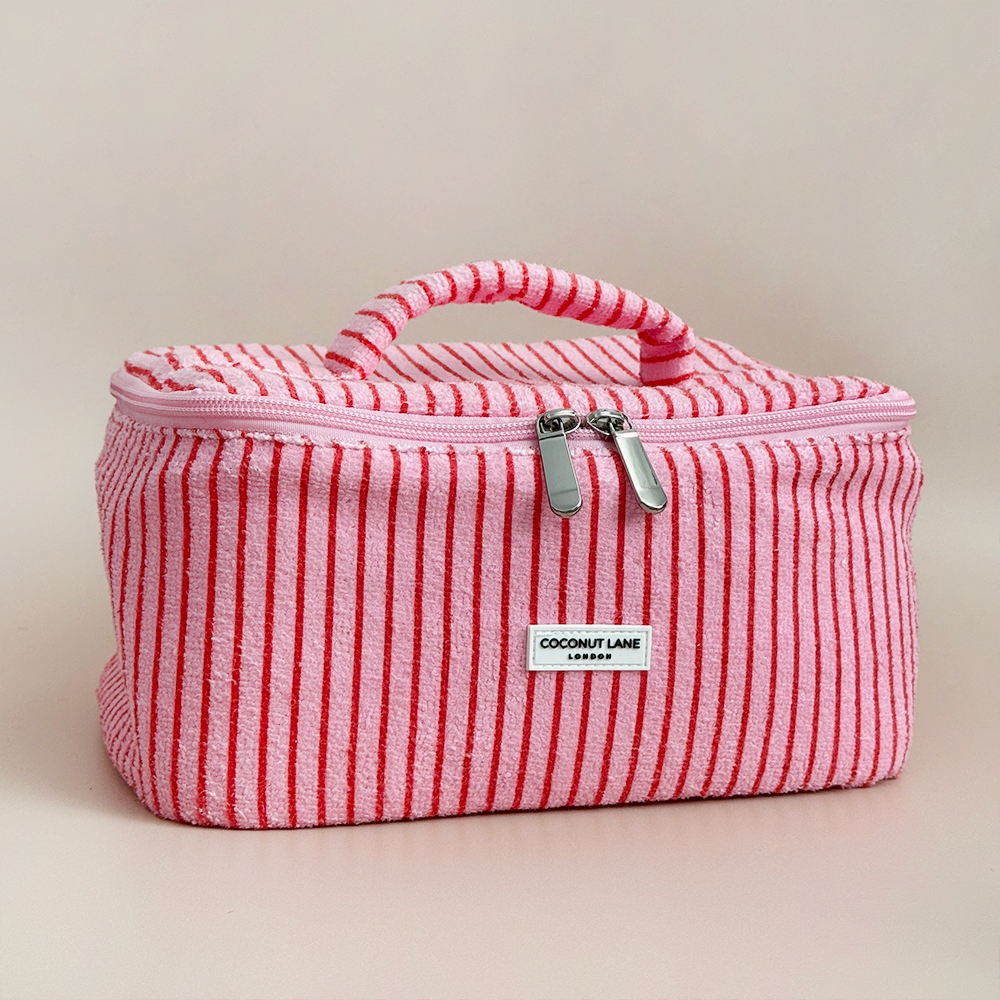 Pink and red striped cosmetic bag with Coconut Lane brand label on a beige background