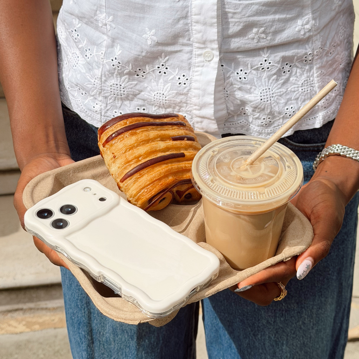 Girl holding a tray with her iced coffee, croissant and wavy phone case cloud dancer