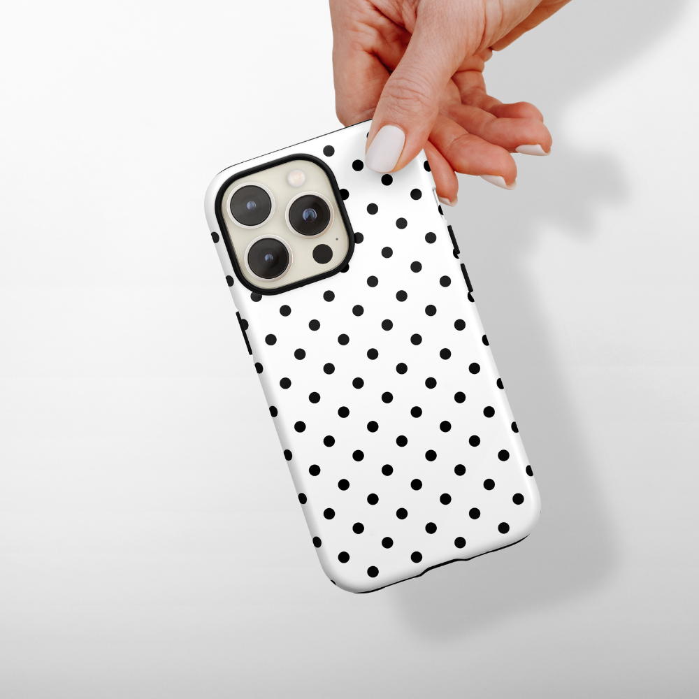 Coconut Lane Tough Phone Case with a white background and bold black polka dots, held in a hand.
