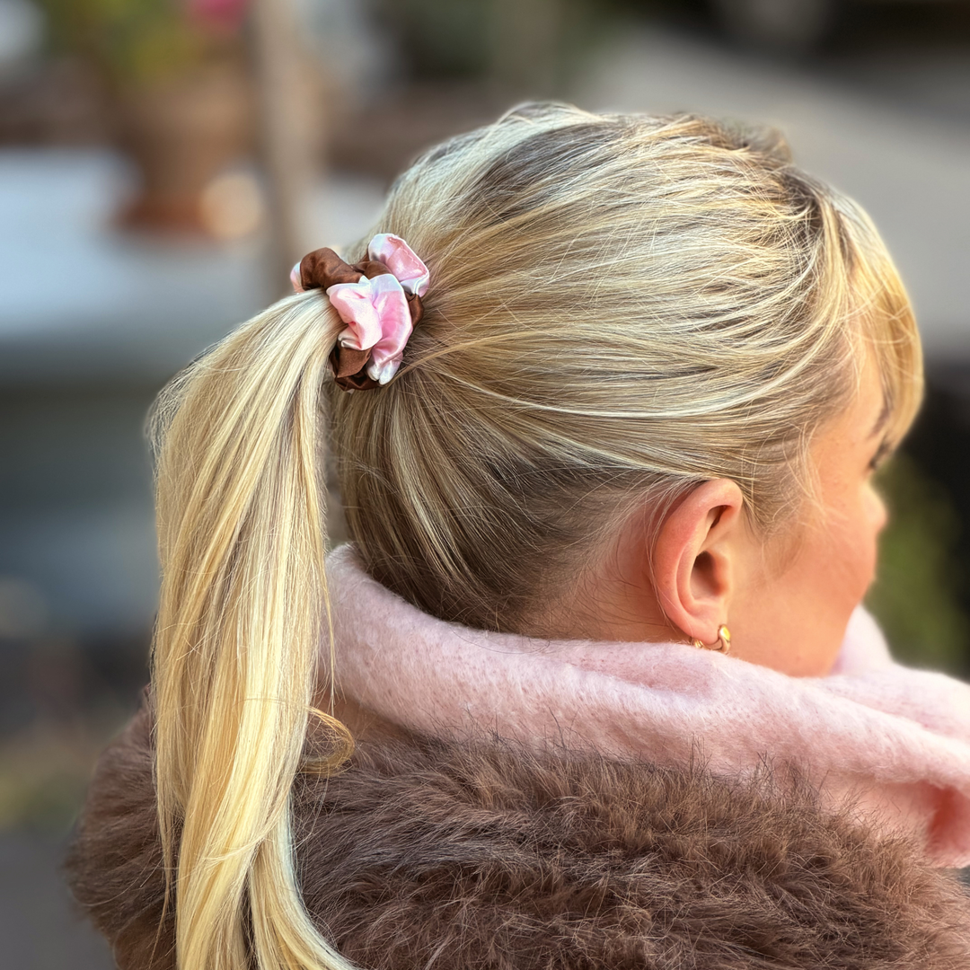 Woman with blonde hair wearing a Satin hair scrunchie in a brown, pink and white striped design.