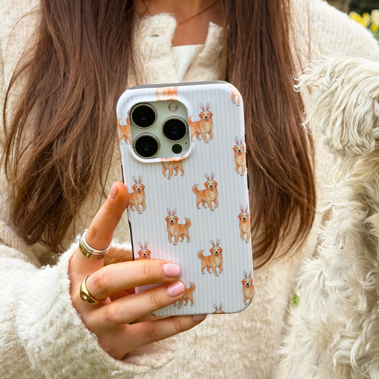 Girl sat next to white dog holding her hoppy pup tough phone case