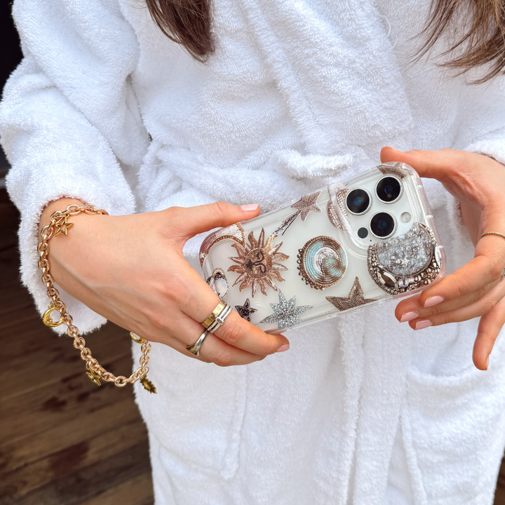 Girl holding pastel celestial phone case with phone strap attached wearing dressing gown